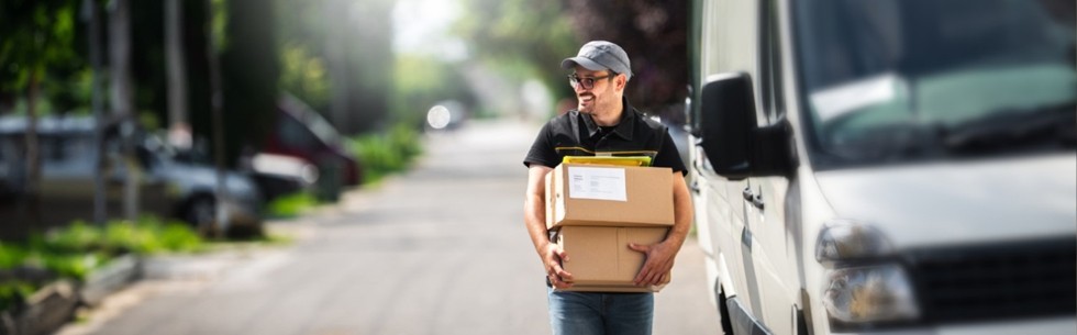 man next to a delivery van carrying packages