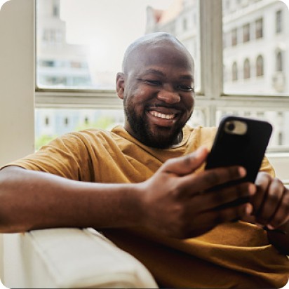 A smiling man performing some action on his cell phone.