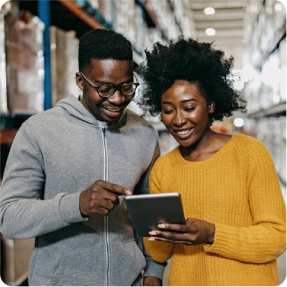 Two smiling people performing some action on a tablet together.